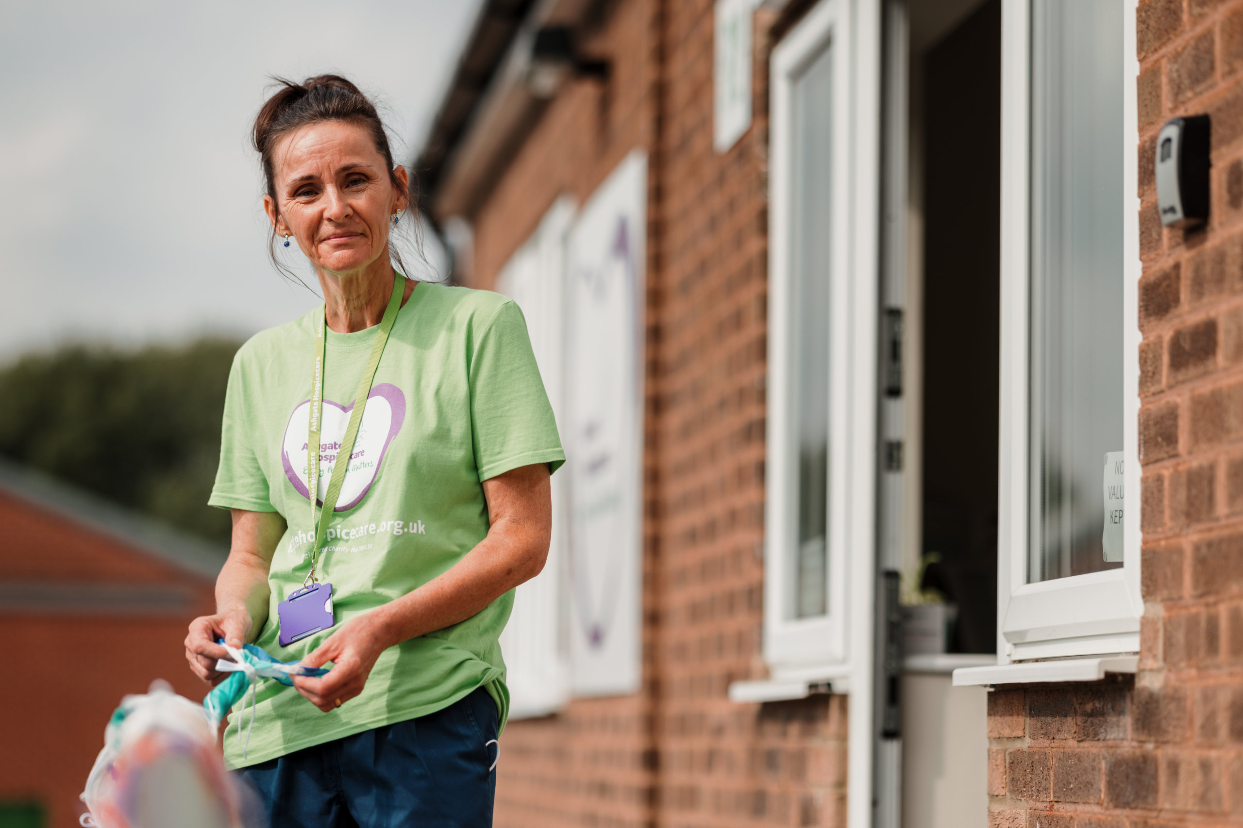 Ashgate Hospice nurse stood outside a building with silk scarves made by patients