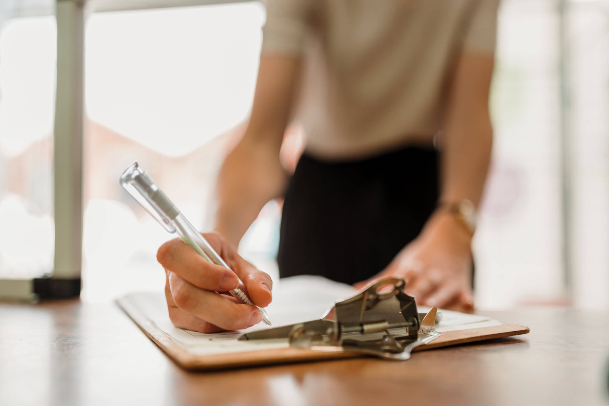 Close up of someone writing on a clipboard with a pen