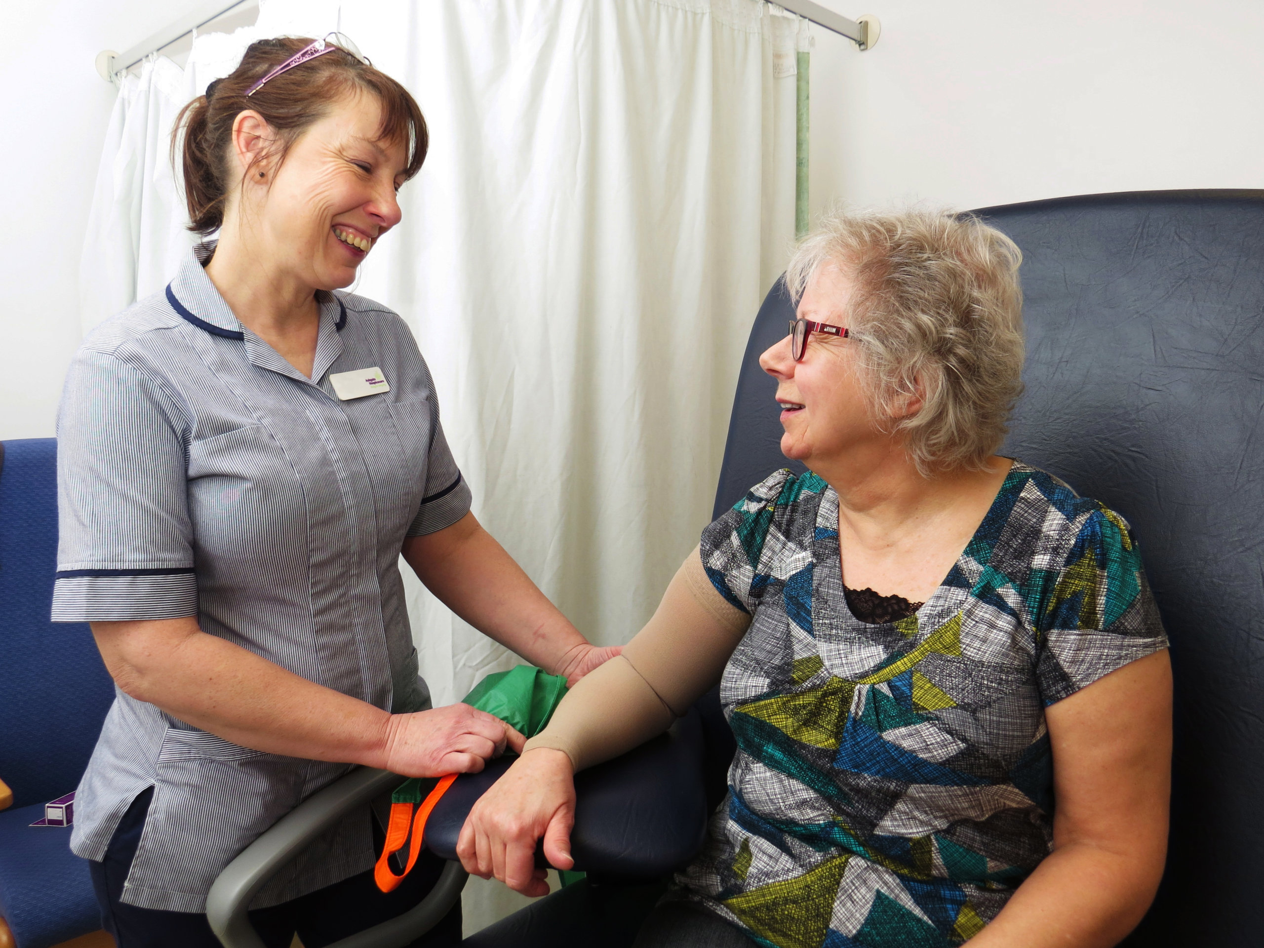 Nurse helping a patient with a lymphoedema compression sleeve