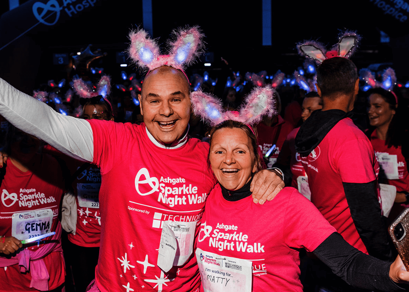 Man and woman at Sparkle Night Walk with arms raised in the air.