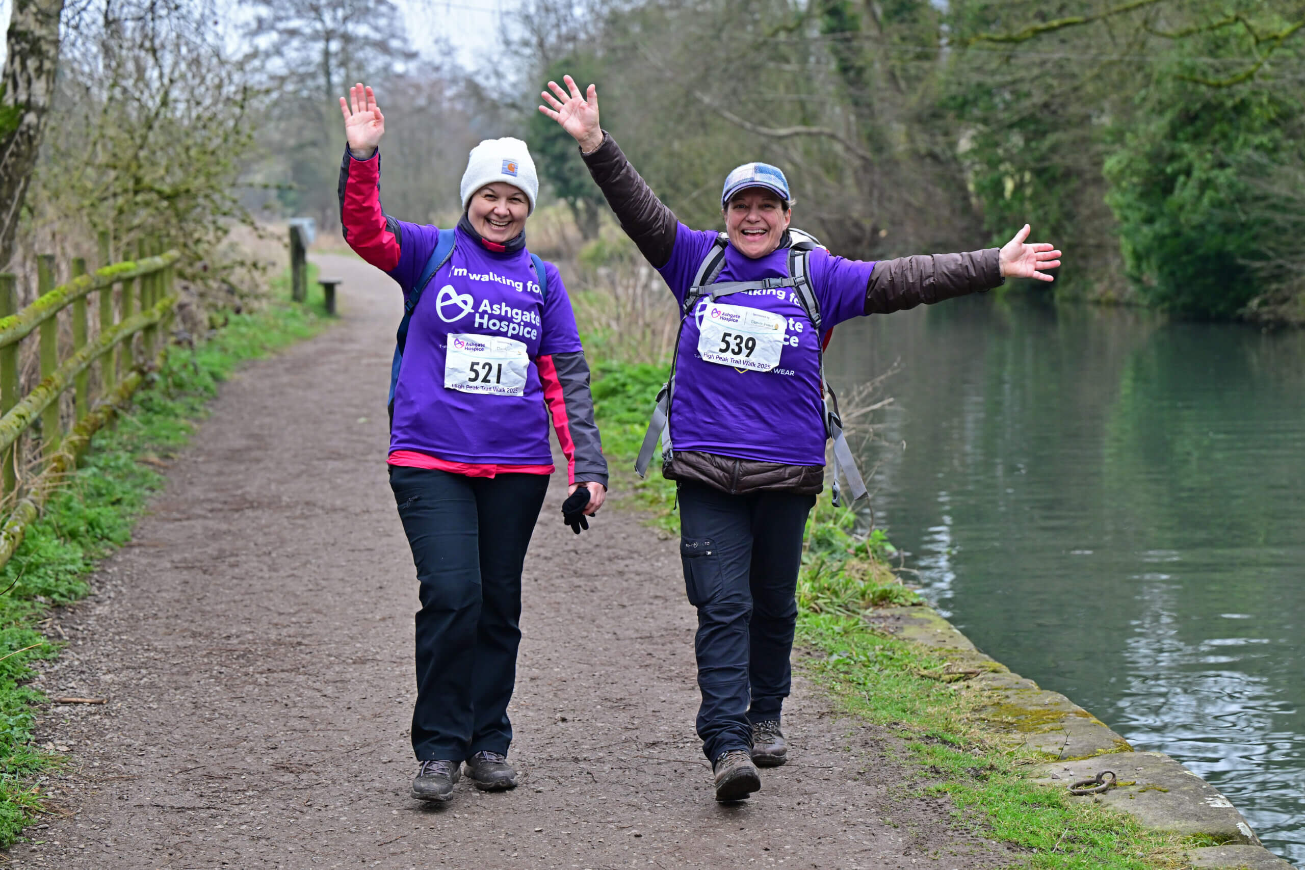 Two people walking along the canal of the High Peak Trail.