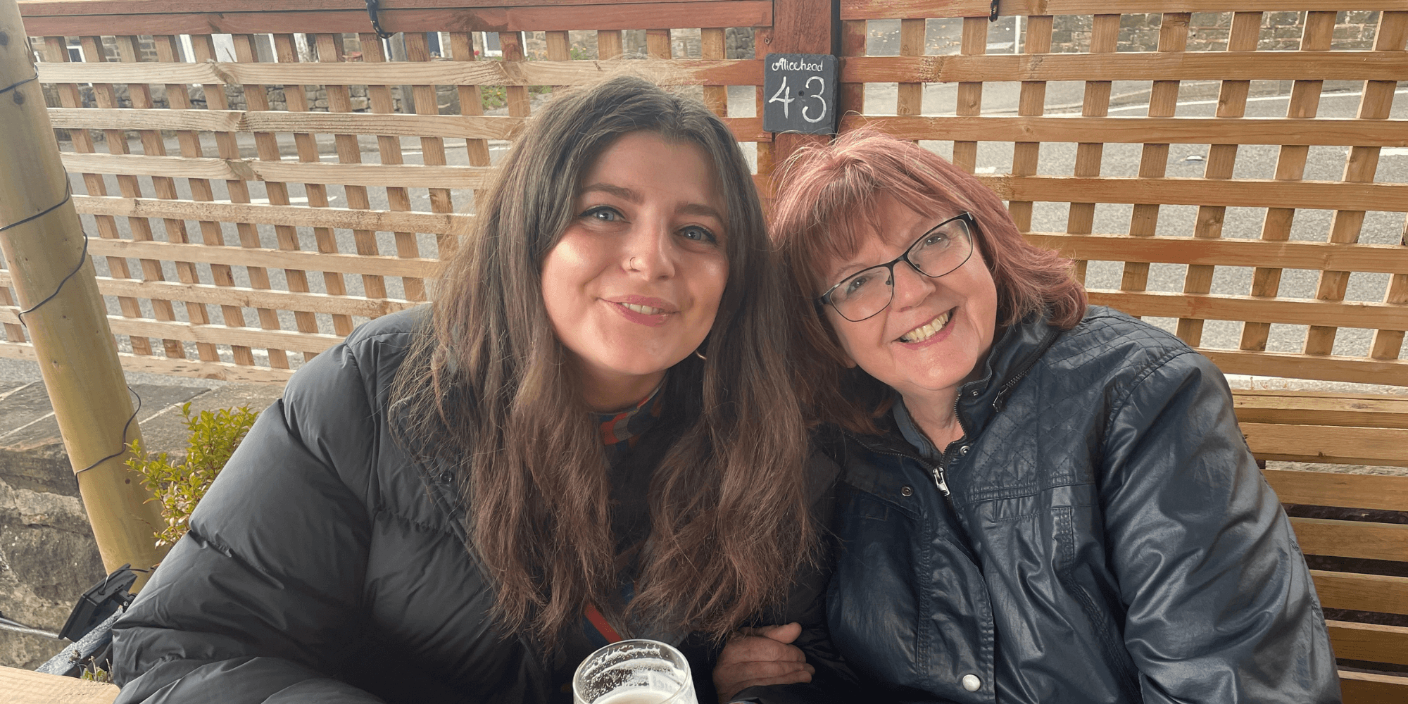 Two women sat together looking at the camera.